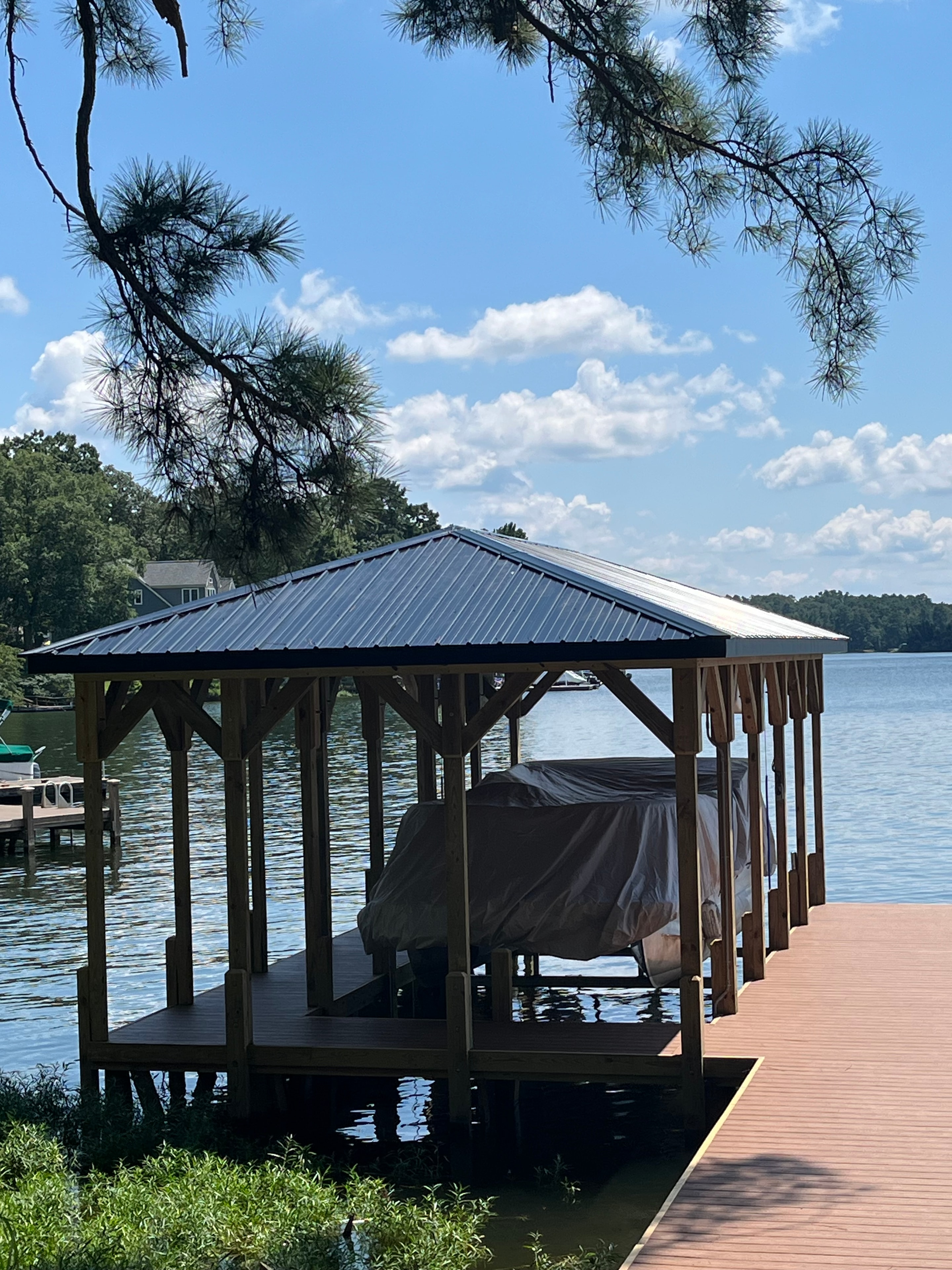 SHT Construction — boathouse side view with metal roof and open boat slip on the water